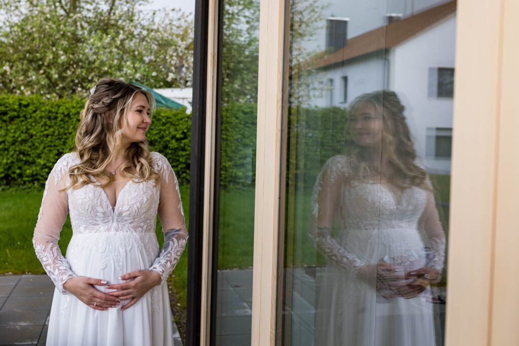 Spiegelung im großen Fenster von der schwangeren Jana auf Ihrer Hochzeit in Mainburg.