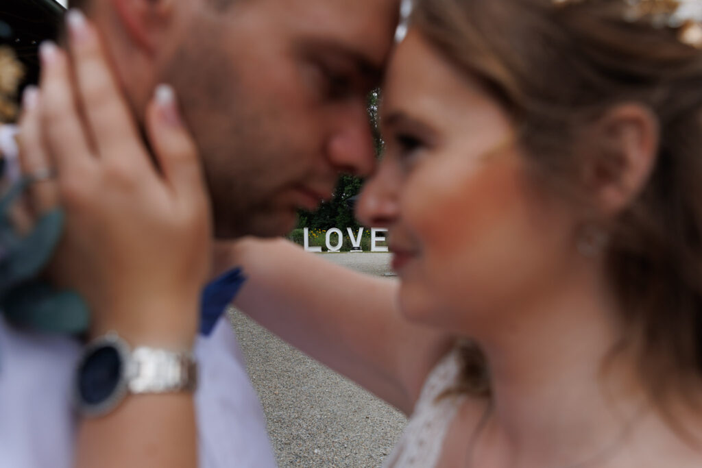 Jessi und Manu beim Brautpaarshooting im Stockerhof Pfaffenhofen. Zu sehen ist das Wort Love zwischen ihnen.
