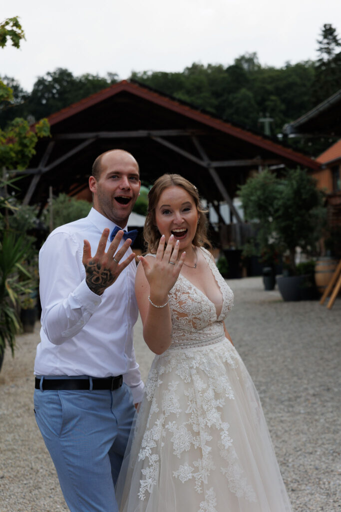 Jessi und Manu strecken uns die Eheringe beim Brautpaarshooting entgegen im Stockerhof Pfaffenhofen.