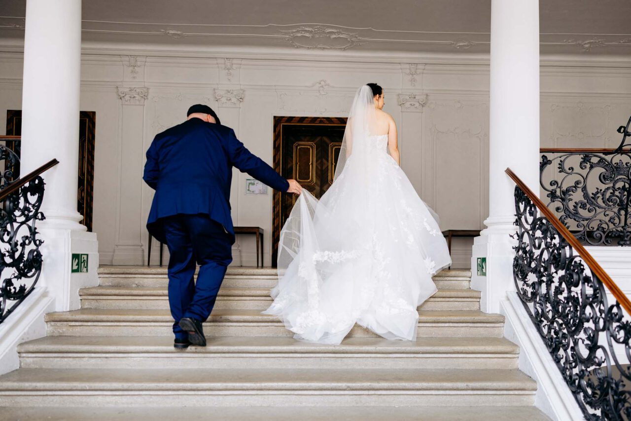 Brautvater und Braut auf den letzten Treppenstufen im Standesamt Einstätt