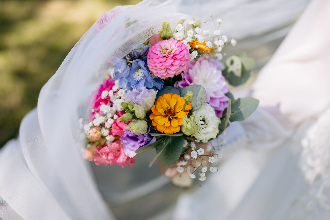 Detailaufnahme vom Brautstrauß im Brautkleid eingewickelt