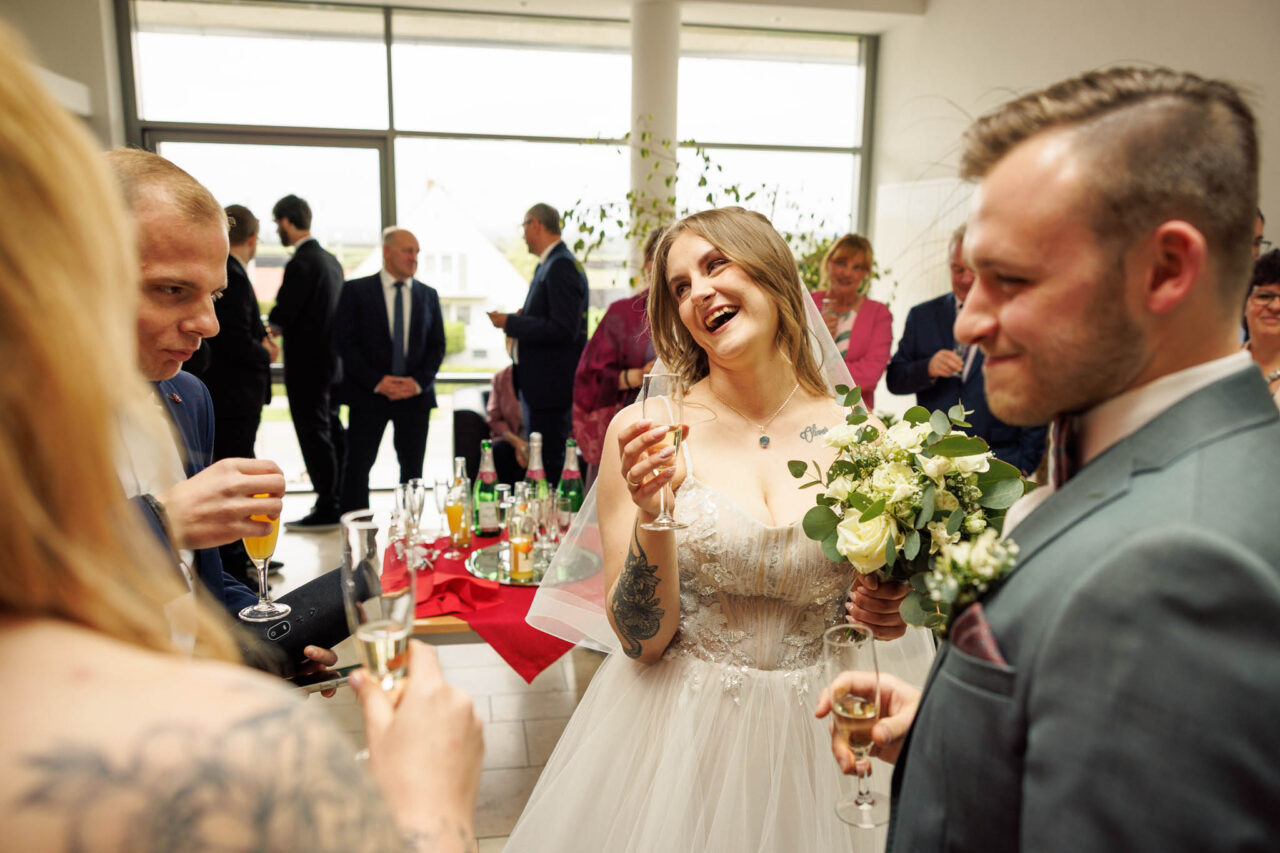 Brautpaar lacht beim Sektempfang im Standesamt Königsmoos