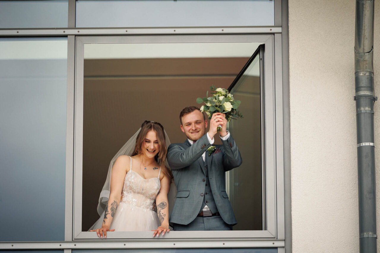 Brautpaar schaut aus dem ersten Stock im Rathaus Königsmoos