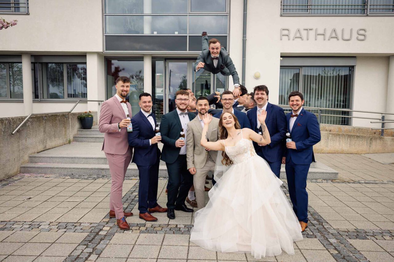 Bräutigam wird in die Luft geworfen von seinen Freunden vor dem Rathaus in Königsmoos