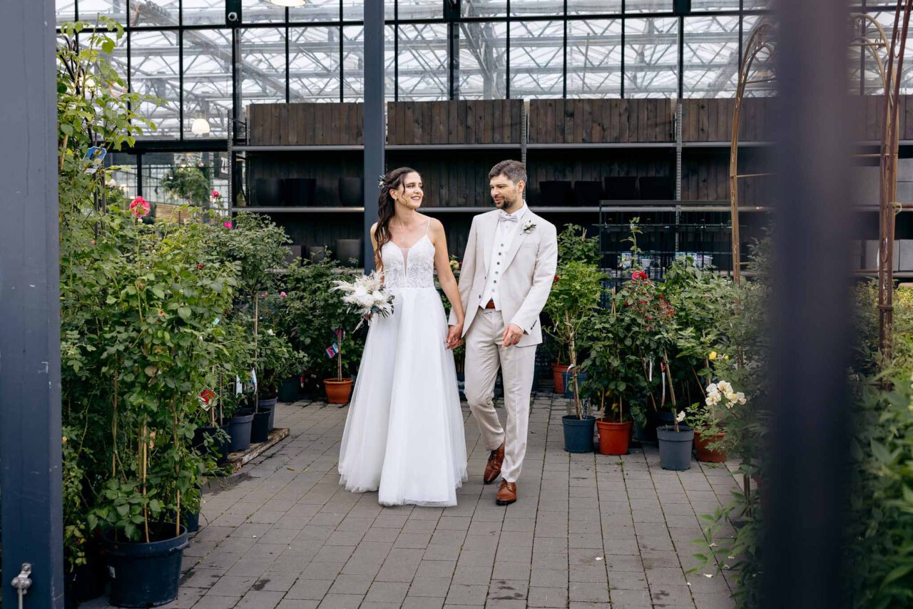 Ein Brautpaar im Außenbereich im Gartencenter Kiefl zwischen Blumentöpfen und Rosen
