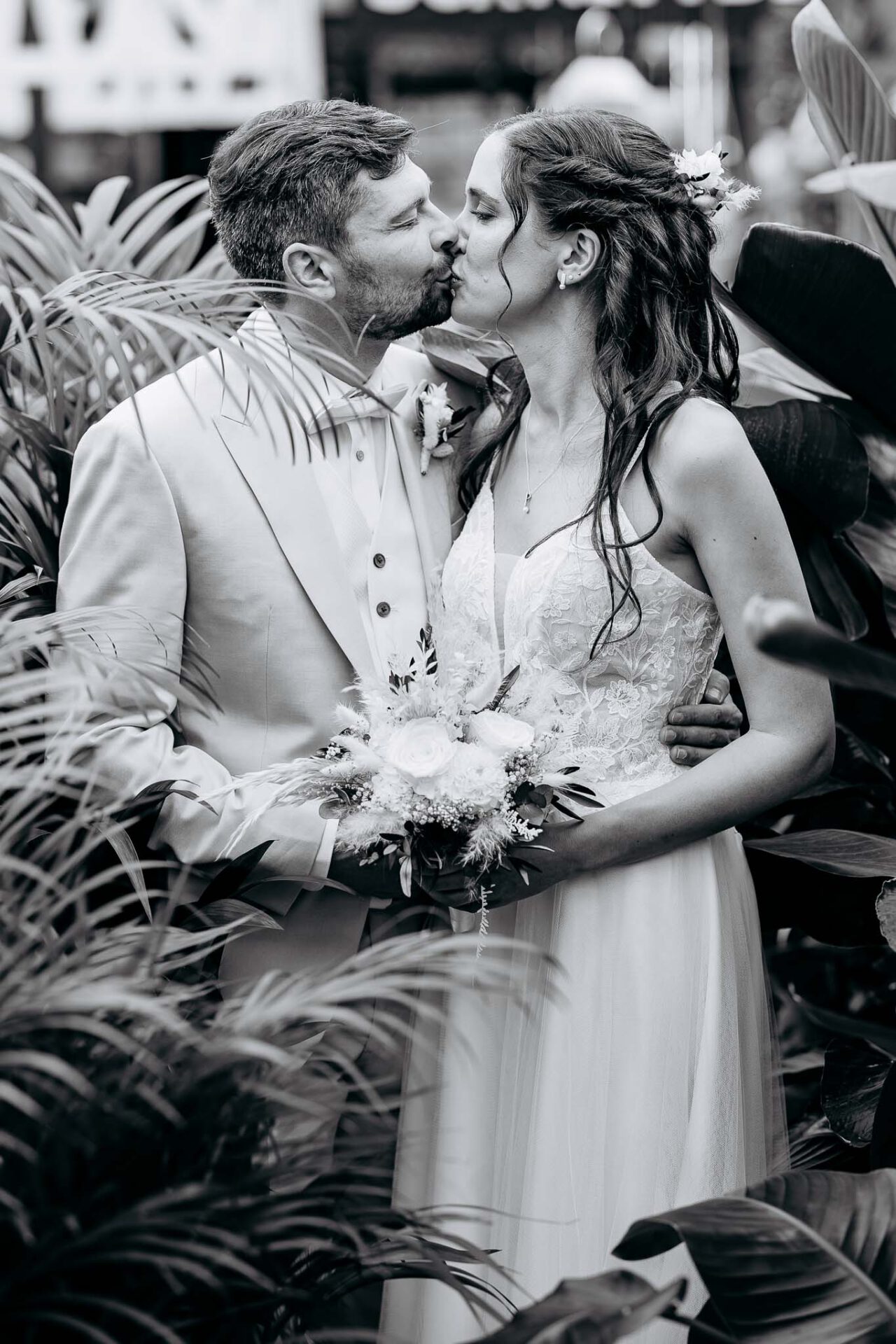 Schwarz Weiß Aufnahme im Portrait das Brautpaar küsst sich umringt von Pflanzen aus dem Gartencenter