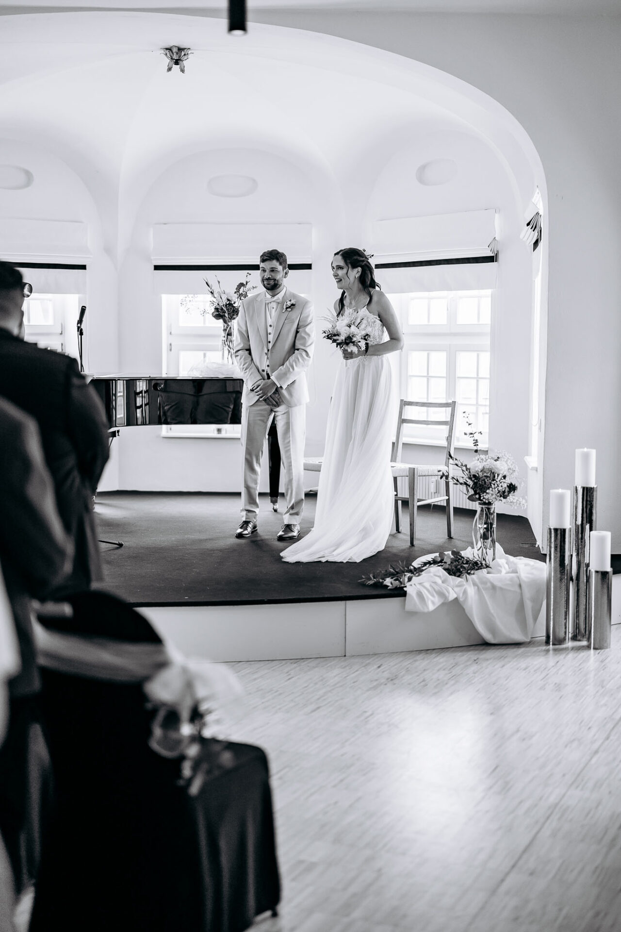 Das Brautpaar strahlt über beide Ohren auf der Bühne im Blauen Saal in Pullach