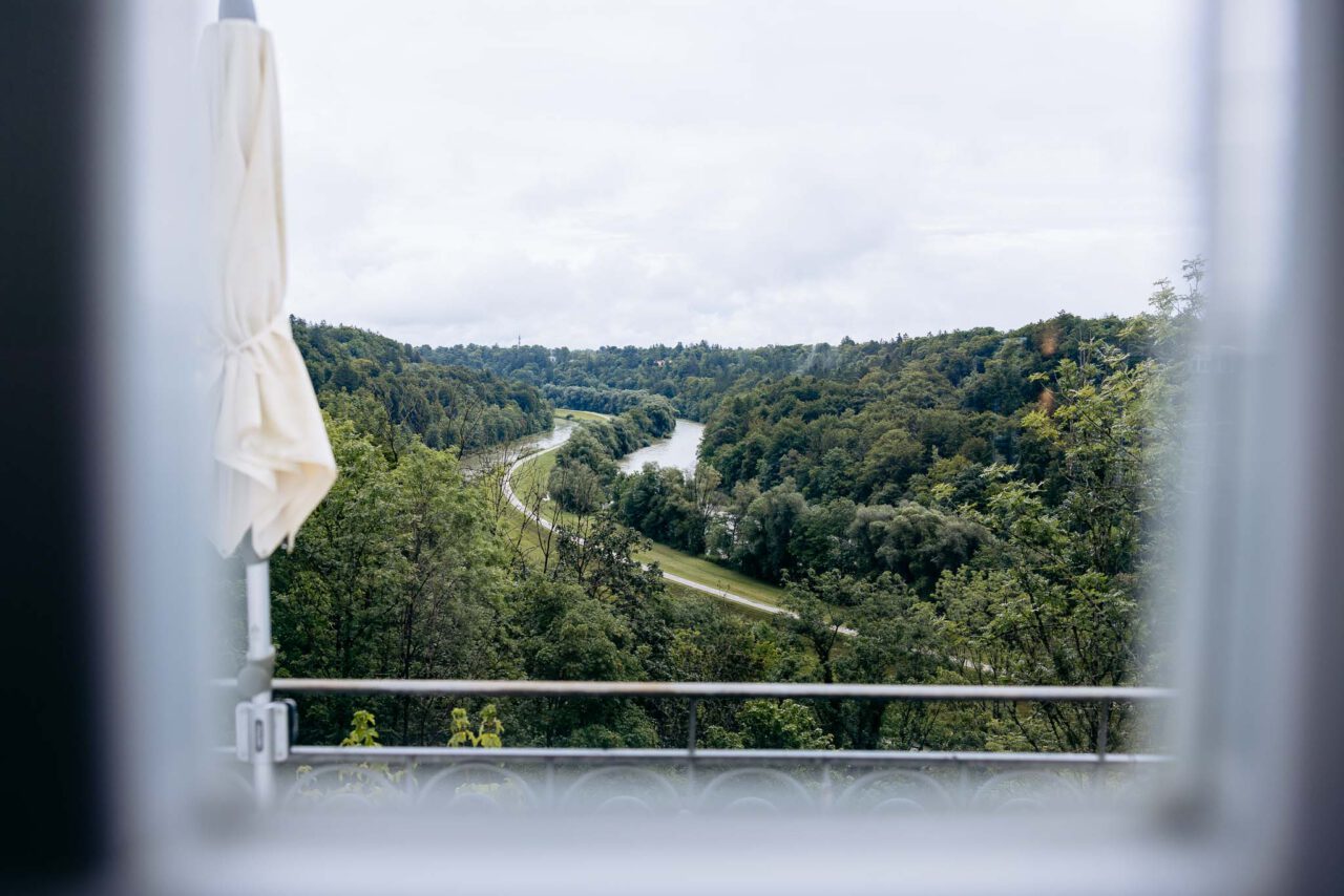 Blick vom Blauen Saal aus dem Fenster über die Isar alles ist grün im August