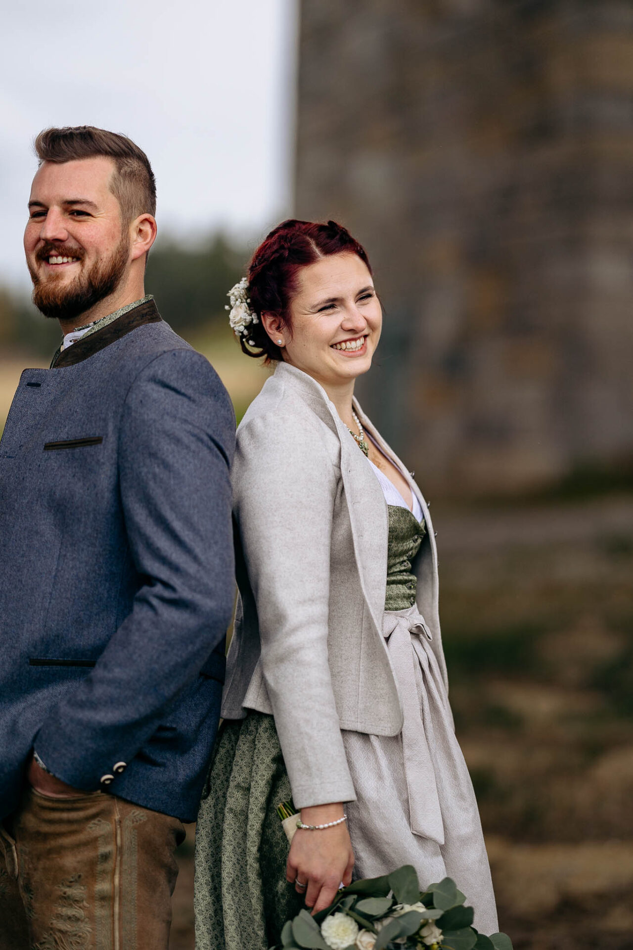 Braut und Bräutigam lachen rücken an Rücken im Brautpaarshooting mit den Hochzeitsfotografen Pfaffenhofen