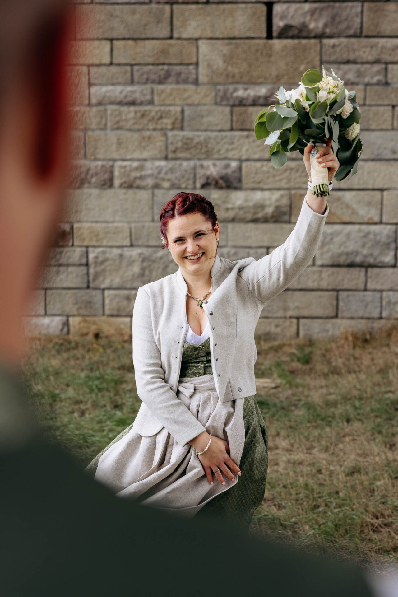 Die Braut schaut ihren Bräutigam lächelnd an und reißt ihren Brautstrauß in die Luft