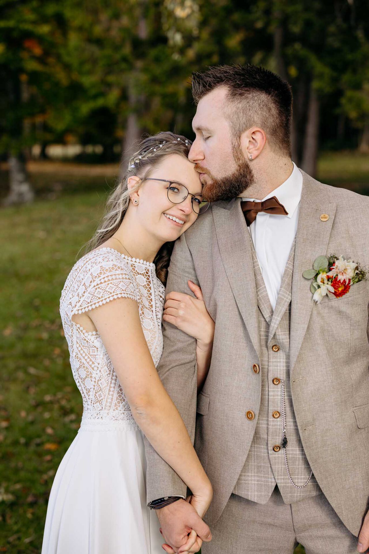 Die Braut lehnt an der Schulter und bekommt einen Kuss auf die Stirn von ihrem Bräutigam am Starnberger See