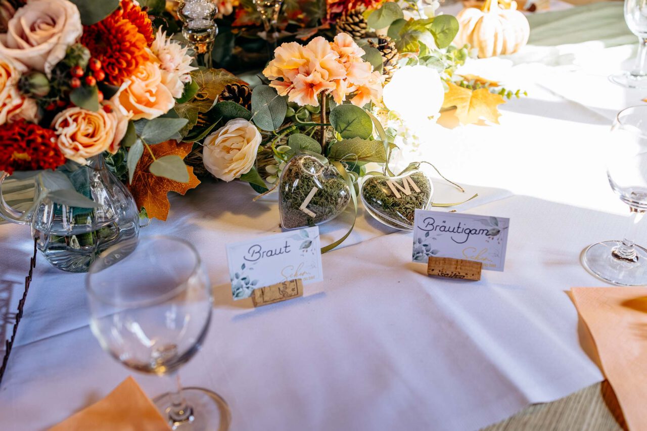Tischkarten und Herzen mit den Initialen des Brautpaares auf dem Brauttisch