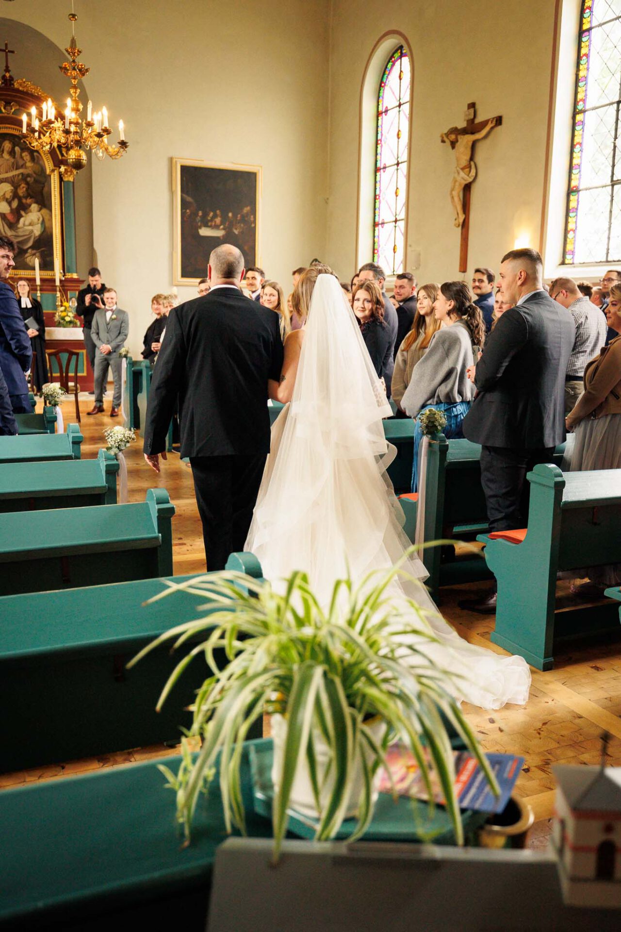 Die Braut schreitet mit ihrem Papa entlang Richtung Altar