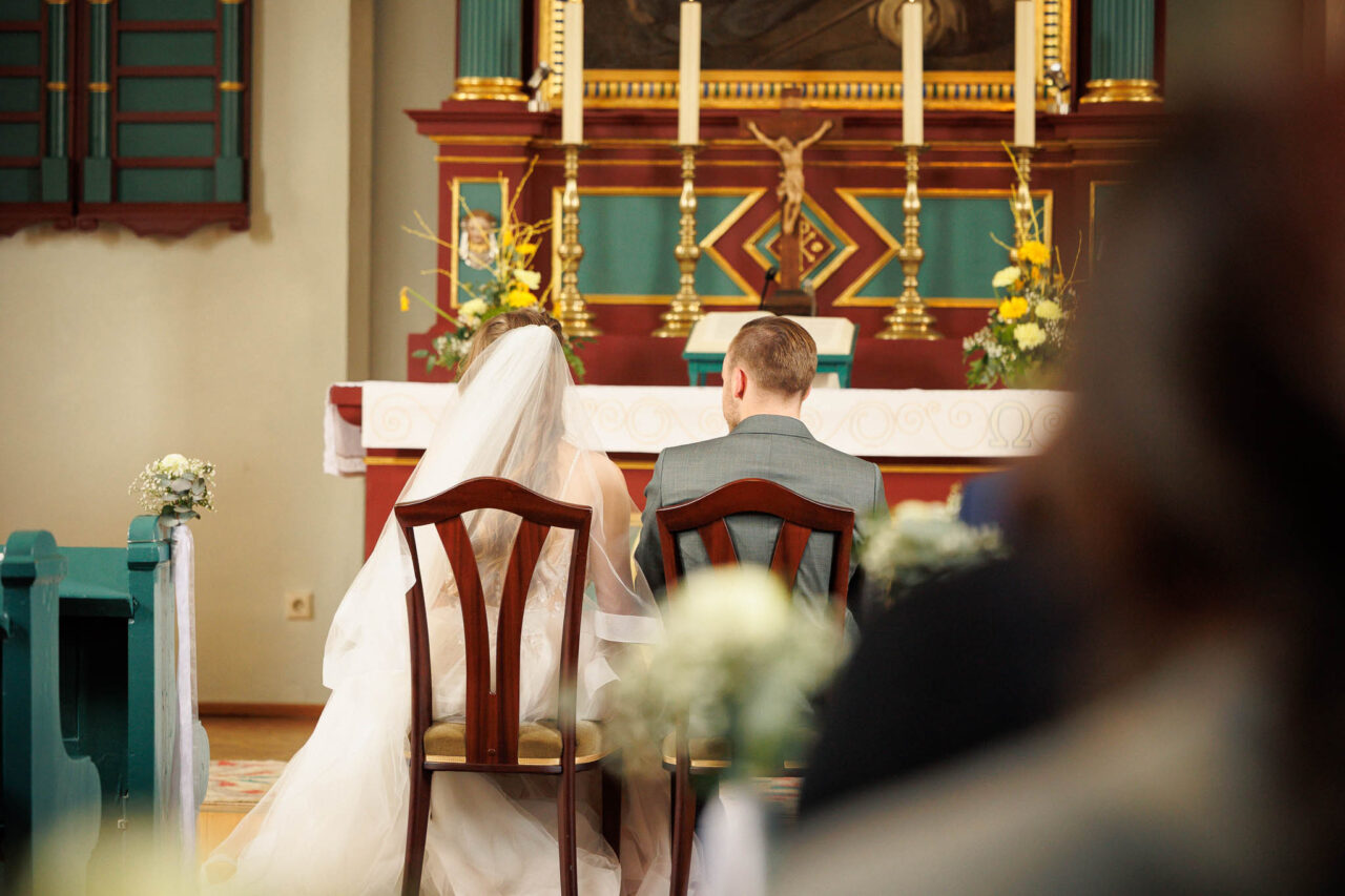Das Brautpaar sitzt in Königsmoos in der Kirche vor dem Altar