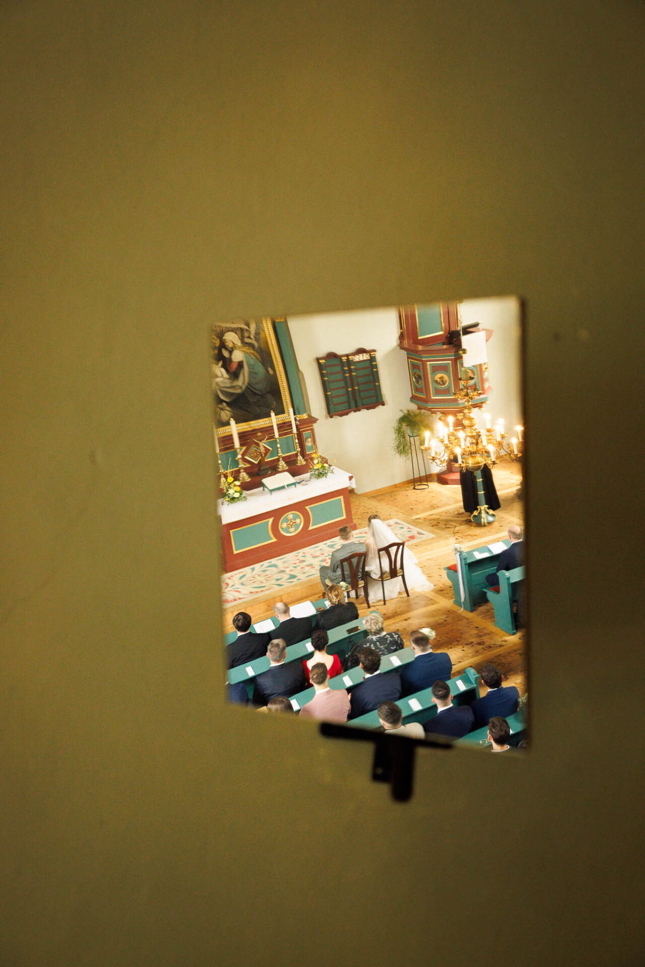 Bild von der Empore in der Kirche Königsmoos durch den Spiegel an der Wand und es ist die Spiegelung vom Brautpaar vor dem Altar zu sehen.