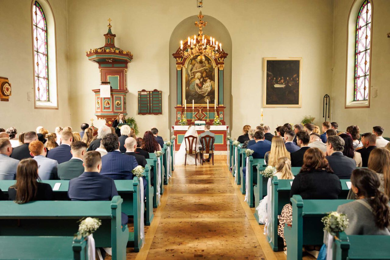 Weitwinkelaufnahme der Kirche in Königsmoos von hinten alle Gäste blicken zum Brautpaar nach vorne